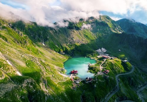 Aerial drone view of nature in Romania. Transfagarasan route in Carpathian mountains, Balea Lake resort and rocky slopes covered with greenery